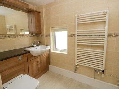 A bathroom with a sink, toilet and mirror at Beach Retreat in Aberporth
