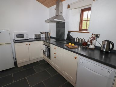 A kitchen with countertop appliances including a microwave toaster and kettle at Panteurig Cottage in Strumble Head Goodwick Pembrokeshire