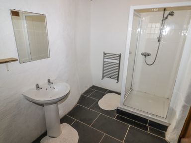 A bathroom with a pedestal sink mirror towel rack and a shower stall at Panteurig Cottage in Strumble Head Goodwick Pembrokeshire
