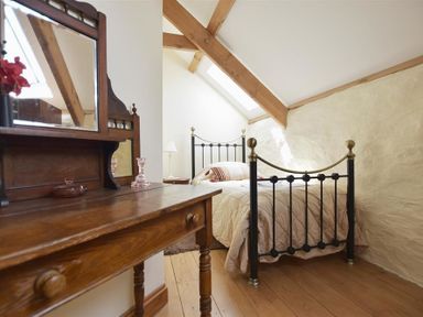 A bedroom with a black metal bed frame wooden dressing table with mirror and wooden floor at Panteurig Farmhouse in Strumble Head Goodwick Pembrokeshire