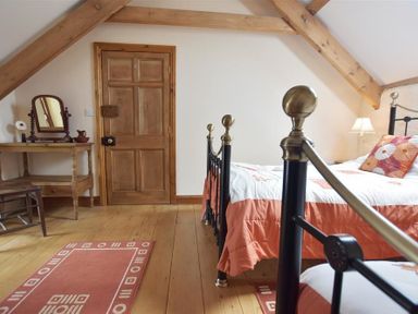 A bedroom with a wooden door a dressing table and a bed with orange bedding at Panteurig Farmhouse Strumble Head Goodwick Pembrokeshire