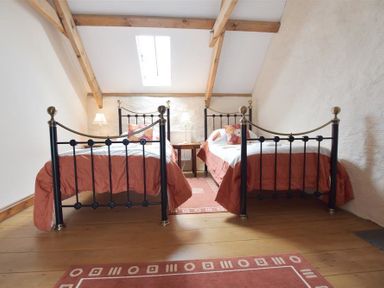A bedroom with two single beds and a skylight at Panteurig Farmhouse in Strumble Head Goodwick Pembrokeshire
