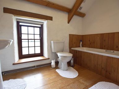 A bathroom with a wooden floor toilet bathtub and window at Panteurig Farmhouse Strumble Head Goodwick Pembrokeshire