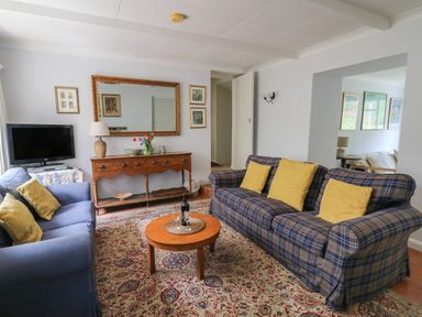 A living room with two sofas a wooden coffee table and a TV on a stand at Yr Odyn in Llangrannog Ceredigion