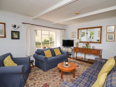 A sitting room with blue sofas yellow cushions a wooden coffee table and a sideboard with a mirror at Yr Odyn in Llangrannog Ceredigion