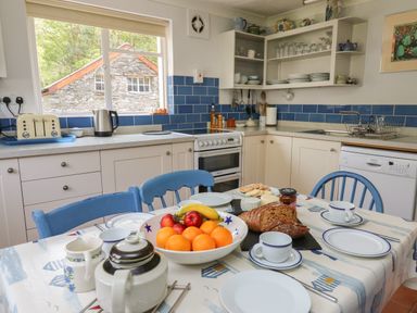 A kitchen with a table set for breakfast including fruit bread and cups at Yr Odyn in Llangrannog Ceredigion