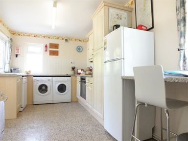 A kitchen with washing machines oven refrigerator and a chair at Granston Cottage in Castlemorris Pembrokeshire