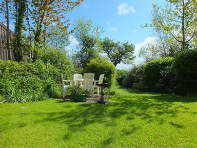 A garden with plastic chairs around a table and a bird bath at Granston Cottage in Castlemorris Pembrokeshire