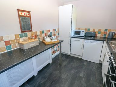 A kitchen with countertops appliances and a tiled backsplash at Newton West Farm in Newton near Newgale