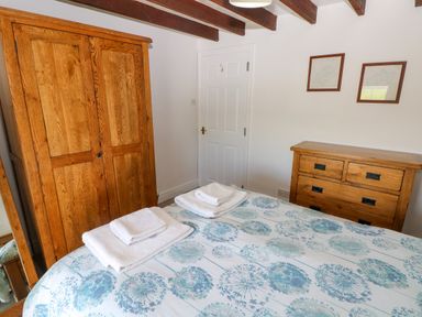A bedroom with a bed, wooden wardrobe, wooden chest of drawers, and two framed pictures on the wall at Newton West Farm Newton near Newgale