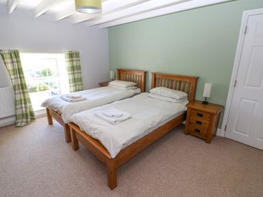 A bedroom with two single wooden beds with white bedding and towels on each bed at Newton West Farm Newton near Newgale