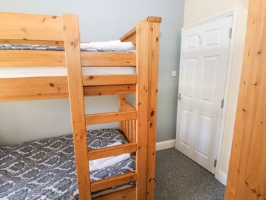 A bedroom with a wooden bunk bed and a white door at Newton West Farm in Newton near Newgale