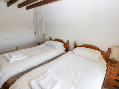 A bedroom with two single wooden beds each with white bedding and folded towels on top at Newton West Farm Newton near Newgale