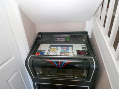 A vintage jukebox placed in a small corner under a staircase