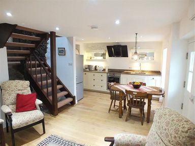 A kitchen and dining area with wooden table and chairs and stairs in a living space at Beach Cottage in Little Haven Pembrokeshire
