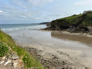 A beach with waves and a cliff at Beach Cottage in Little Haven, Pembrokeshire