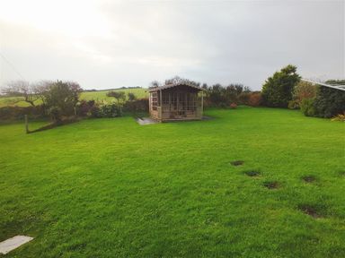 A garden with a wooden gazebo surrounded by grass and bushes at Gwndwn Gwyn in Trefasser near Strumble Head