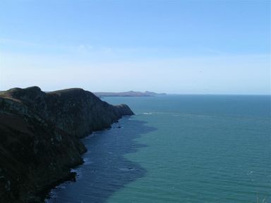 A coastline with rocky cliffs and ocean water under a clear sky at Gwndwn Gwyn Trefasser Near Strumble Head