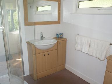 A bathroom with a sink cabinet mirror towels on a rack and a shower enclosure at Beach Cove in Freshwater East Pembrokeshire