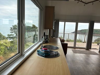 A kitchen with a sink and sea view at Beach Cove Freshwater East Pembrokeshire
