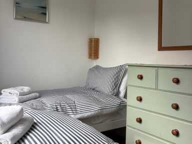 A bedroom with two beds and a dresser at Beach Cove, Freshwater East, Pembrokeshire
