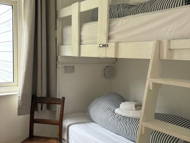 A bedroom with bunk beds and a chair at Beach Cove in Freshwater East, Pembrokeshire