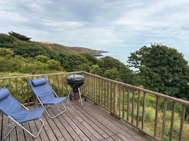 A deck with chairs and a barbecue at Beach Cove Freshwater East, Pembrokeshire