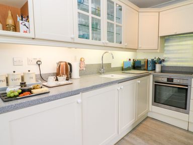 A kitchen with white cabinets gray countertops a sink an oven a kettle and jars on the counter at 5 The Coach House Broad haven Pembrokeshire
