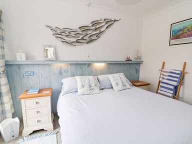 A bedroom with a bed pillow nightstands and a ladder with towels at 5 The Coach House in Broad haven Pembrokeshire