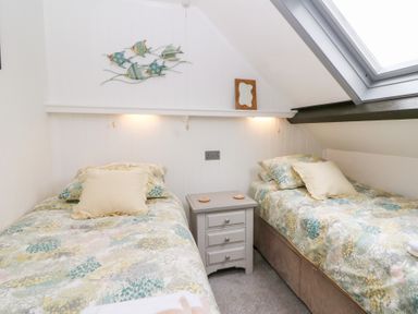 A small bedroom with two single beds a nightstand between them and a skylight window at 5 The Coach House in Broad haven Pembrokeshire
