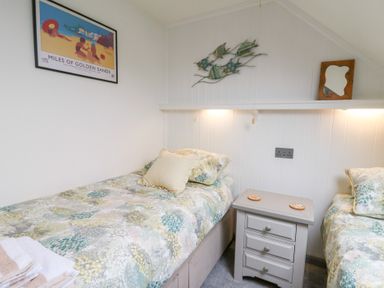 A bedroom with two single beds with patterned bedding and a gray nightstand between them at 5 The Coach House in Broad haven Pembrokeshire