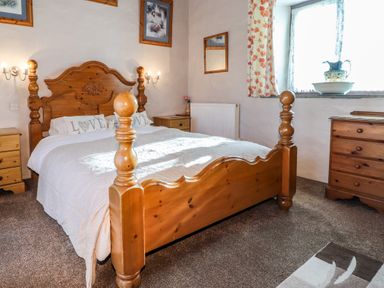 A bedroom with a wooden bed and two nightstands at Y Stabl in Fishguard Pembrokeshire