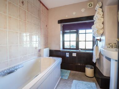 A bathroom with a bathtub toilet window towels and a sink at Y Stabl Fishguard Pembrokeshire