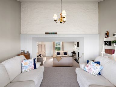 A sitting room with two white sofas and a view into another sitting area with more sofas at The Rock House in Fishguard Pembrokeshire