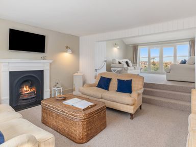 A living room with sofas a fireplace a TV and a wicker coffee table at The Rock House in Fishguard Pembrokeshire
