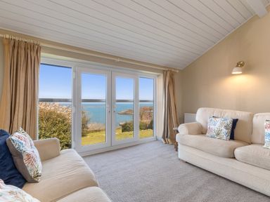 A living room with two sofas and large windows overlooking the sea at The Rock House in Fishguard Pembrokeshire