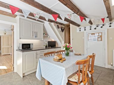 A kitchen with a dining table covered with a blue polka dot tablecloth and wooden chairs at The Rock House in Fishguard Pembrokeshire