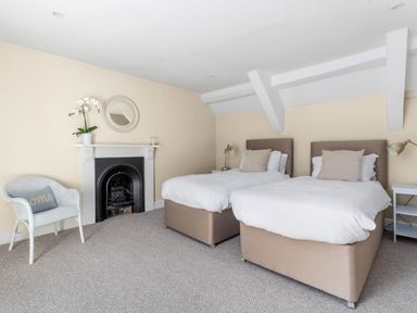A bedroom with two single beds a chair and a fireplace at The Rock House in Fishguard Pembrokeshire