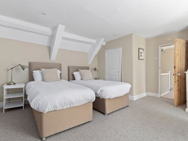 A bedroom with two single beds side by side with white bedding beige headboards and a small bedside table with a lamp at The Rock House in Fishguard Pembrokeshire