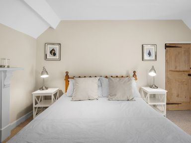 A bedroom with a wooden bed and two bedside tables with lamps and framed pictures on the wall at The Rock House in Fishguard Pembrokeshire