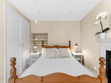 A bedroom with a wooden bed white bedside tables lamps and a potted plant at The Rock House in Fishguard Pembrokeshire