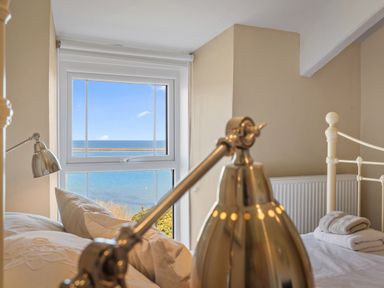A bedroom with a bed towels and a window showing a sea view at The Rock House in Fishguard Pembrokeshire