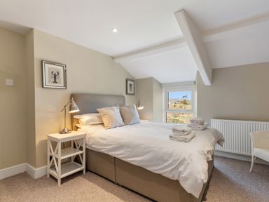 A bedroom with a bed white linens bedside tables lamps and a window at The Rock House in Fishguard Pembrokeshire