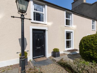 The exterior of a house with a black door two windows a street lamp and shrubs at The Rock House Fishguard Pembrokeshire