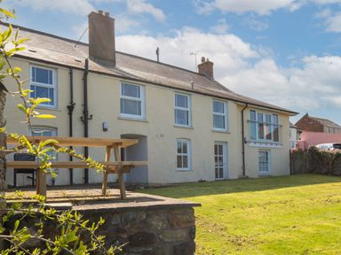 Exterior view of a two story house with multiple windows a picnic table on a patio and a lawn at The Rock House in Fishguard Pembrokeshire