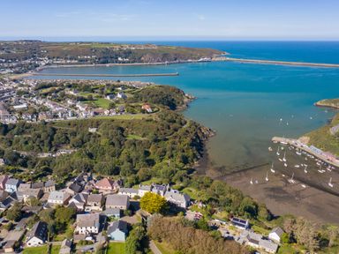 A coastal town with houses trees and boats in the water at The Rock House in Fishguard Pembrokeshire