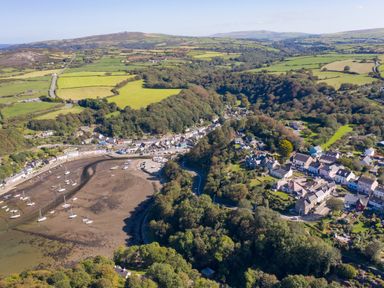 A coastal village with boats on the shore and surrounding green fields at The Rock House in Fishguard Pembrokeshire