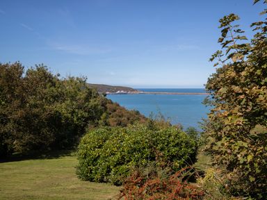 A view of a bay with a ship in the distance and greenery in the foreground at The Rock House in Fishguard Pembrokeshire