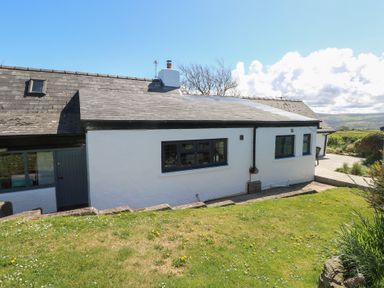 An exterior view of a white cottage with black windows and a grassy garden at Ty-Newydd Cottage Nevern near Newport Pembrokeshire