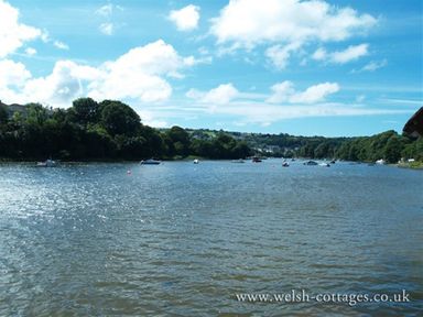 A river with boats and trees along the shore under a blue sky at Stable Cottage Cardigan in Cardigan Ceredigion